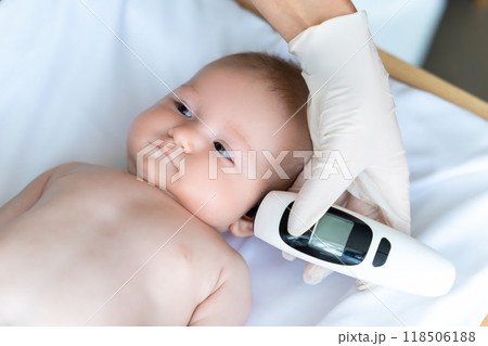 Doctor using infrared ear thermometer to check baby boy's temperature during medical examination 118506188