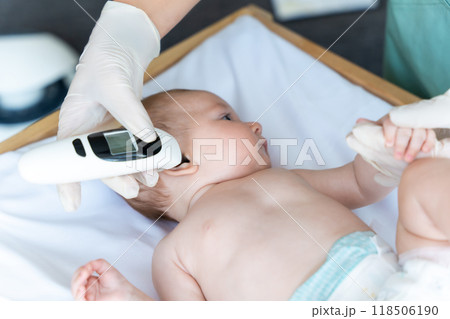 Female pediatrician with digital infrared thermometer measuring baby girl patient's ear temperature Female pediatrician with digital infrared thermometer measuring baby girl patient's ear temperature 118506190