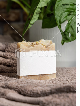 Soap bar with blank label on brown folded towels near green plant in bathroom, mockup Soap bar with blank label on brown folded towels near green plant in bathroom, mockup 118506292