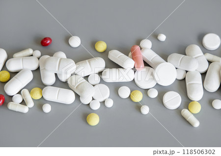 Mix of medical capsules and pills in a line on grey close up. Medicinal treatment 118506302