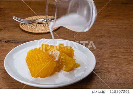 High angle view pouring coconut milk on cassava or tapioca in syrup. High angle view pouring coconut milk on cassava or tapioca in syrup. 118507291