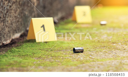 Spent bullet casing lying on the ground with blur number 1 sign. Concepts of shooting sports and security highlighting the dual nature of firearms in both competitive sport and protective measures. Spent bullet casing lying on the ground with blur number 1 sign. Concepts of shooting sports and security highlighting the dual nature of firearms in both competitive sport and protective measures. 118508433