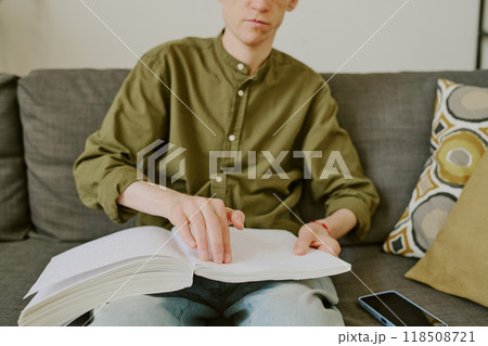 Medium close up of Braille book on knees of unrecognizable man with disability 118508721