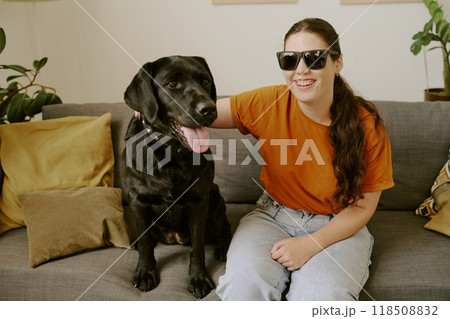 Smiling young Caucasian blind woman with sunglasses smiling widely and petting her loyal friend 118508832