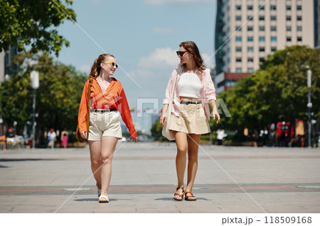 Two Women Walking Down City Street in Daylight 118509168