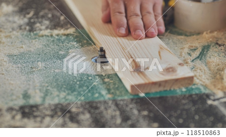 Close up of a carpenter working wood plank using electric milling machine in workshop Close up of a carpenter working wood plank using electric milling machine in workshop 118510863