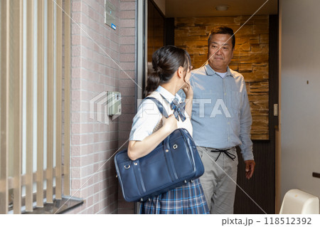 玄関で女子高生の娘を見送る父親 118512392