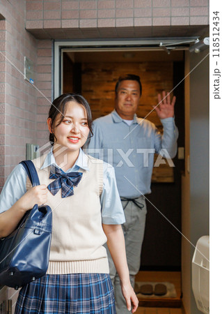 玄関で女子高生の娘を見送る父親 118512434