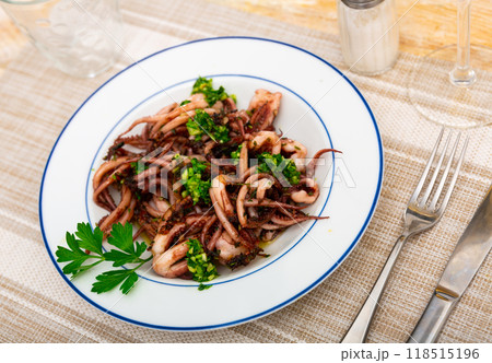 Fried tentacles squid served on white plate with potatoes, lemon slices 118515196