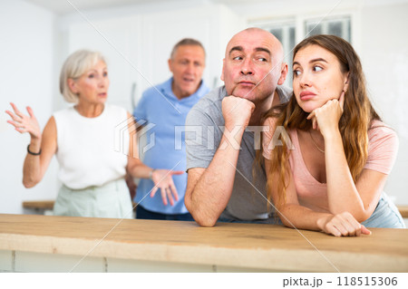 Husband and wife listen to their parents scold them in home kitchen 118515306