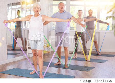 Elderly woman during Pilates strength training standing performs exercises resistance band 118515450