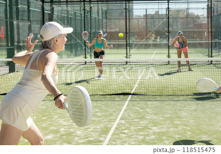 Motivated senior woman playing padel with her teammate in court 118515475