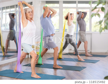 Elderly woman during Pilates strength training standing performs exercises resistance band 118515492