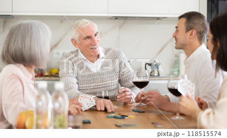 Joyful senior parents and young couple sitting around table playing poker 118515574