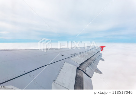 View from the airplane window at a beautiful cloudy sky and the airplane wing View from the airplane window at a beautiful cloudy sky and the airplane wing 118517046