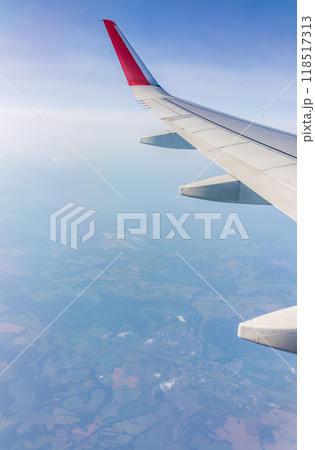 View from the airplane window at a beautiful cloudy sky and the airplane wing View from the airplane window at a beautiful cloudy sky and the airplane wing 118517313