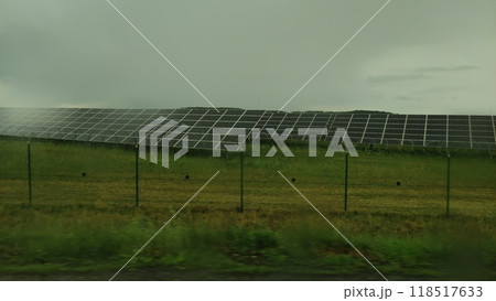 Solar panels generating electricity behind barbed wire fence on cloudy day 118517633