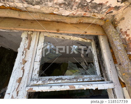 Broken window of an abandoned building with peeling paint Broken window of an abandoned building with peeling paint 118517739