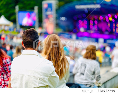 Couple enjoying outdoor concert with vibrant lights and crowd 118517749