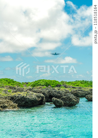 沖縄の海を飛行する旅客機 118518164