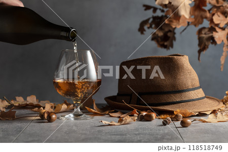 Brandy is poured from a bottle into a glass. Brandy is poured from a bottle into a glass. 118518749