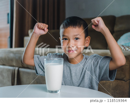 Concept of happy good nutrition, Portrait of a little young handsome kid boy in grey t-shirt, Show a glass of milk Inside a modern home background, Smiling of Asian boy with a glass of milk. 118519364