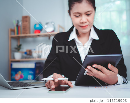Business Woman in black suit working on tablet, Smartphone with laptop and tablet on office table, Hand touch on tablet at office with white background, Online working, Close up, Copy space. 118519998