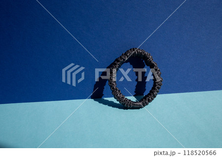 a dark blue silk hair scrunchie for women sitting on top of a blue and cyan surface, minimalism, 118520566