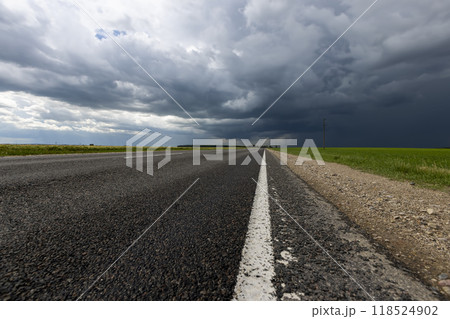 narrow rural paved road before a thunderstorm narrow rural paved road before a thunderstorm 118524902