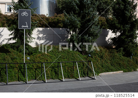 Parking area for bicycles and scooters with mounts for the safety of personal vehicles. Sign on pole shows where to park scooters and bicycles in public park Parking area for bicycles and scooters with mounts for the safety of personal vehicles. Sign on pole shows where to park scooters and bicycles in public park 118525514