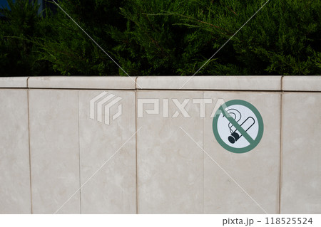 Sticker on stone fence prohibiting smoking in park. Taking care of plants and preventing fire due to smoking in dangerous place, banning smoking in special area 118525524