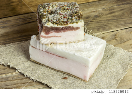 On a wooden surface on a napkin lies a rustic salted bacon On a wooden surface on a napkin lies a rustic salted bacon 118526912