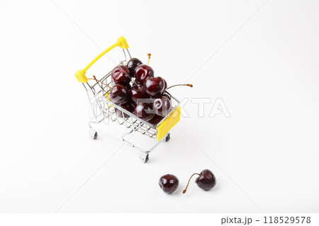 Cherry in a miniature (small) grocery cart for a supermarket. Toy cart with berries on a white background. Close-up, Copy space for text, top view. Cherry in a miniature (small) grocery cart for a supermarket. Toy cart with berries on a white background. Close-up, Copy space for text, top view. 118529578