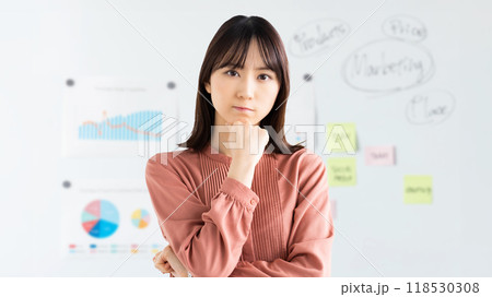 ホワイトボードの前で考えごとをする若いビジネスウーマン ホワイトボードの前で考えごとをする若いビジネスウーマン 118530308