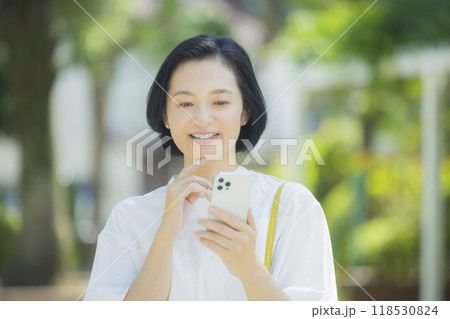スマホを持つ笑顔のミドル女性 118530824