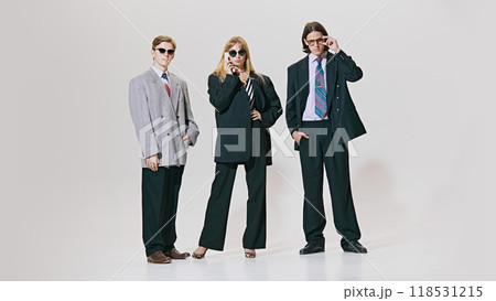 Three confident professionals stand tall in oversized suits and sharp ties, combining classic business style with bold, modern edge. Three confident professionals stand tall in oversized suits and sharp ties, combining classic business style with bold, modern edge. 118531215