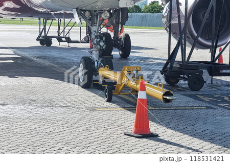 Close-up of aircraft towbar next to airplane wheel in preparation for pushback before departture 118531421