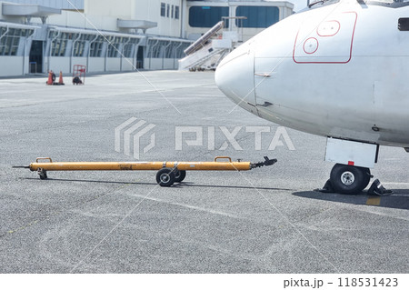Close-up of aircraft towbar next to small airplane wheel in preparation for pushback before departture Close-up of aircraft towbar next to small airplane wheel in preparation for pushback before departture 118531423