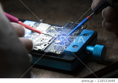 Side view of mechanic doing repairs Smartphone motherboard, smartphone repair, circuit repair 118531644