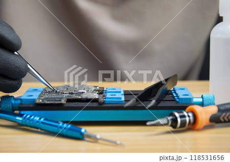 Technician is repairing Smartphone motherboard, circuit repair Technician is repairing Smartphone motherboard, circuit repair 118531656