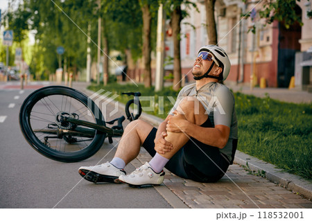 Bicyclist holding injured leg after falling from bicycle having accident 118532001