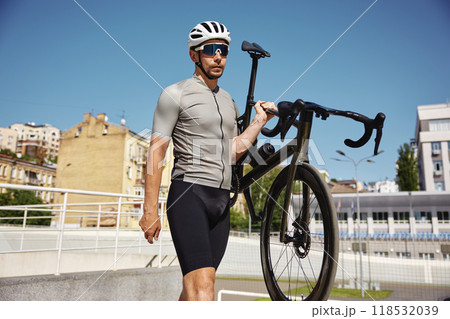 Athletic bicyclist in sportswear carrying bike walking after training workout Athletic bicyclist in sportswear carrying bike walking after training workout 118532039