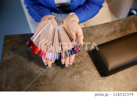Woman client choosing color for manicure on nail polish coating palette 118532374