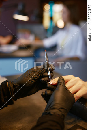 Closeup of master manicurist doing manicure for client at beauty salon 118532376