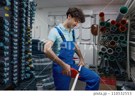 Salesman cutting pipe for client of plumbing hypermarket shop cropped shot 118532553