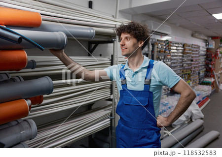 Cheerful man plumber choosing supplies for pipework at plumbing shop Cheerful man plumber choosing supplies for pipework at plumbing shop 118532583