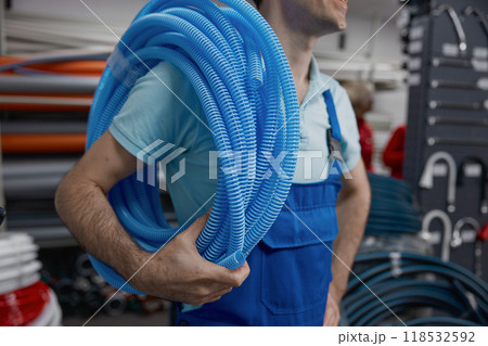 Plumber holding roll of corrugated plastic water pipe 118532592