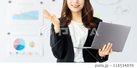 パソコンを持って案内をする笑顔の女性 118534839