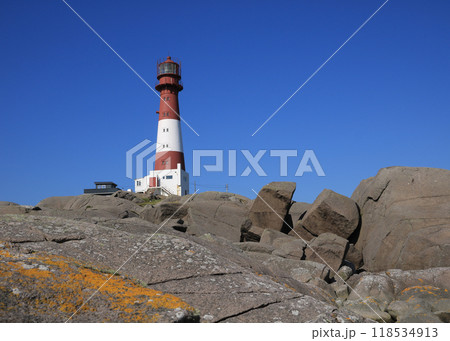 Red and white cast iron Eigeroy Lighthouse and anorthosite rock formations, Norway. 118534913