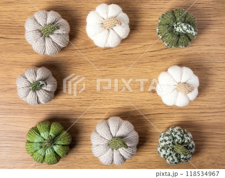 Knitted white, green and beige pumpkins on brown wooden background with place for text. Concept of autumn, Halloween, Thanksgiving. Handmade work. Flat lay, copy space 118534967
